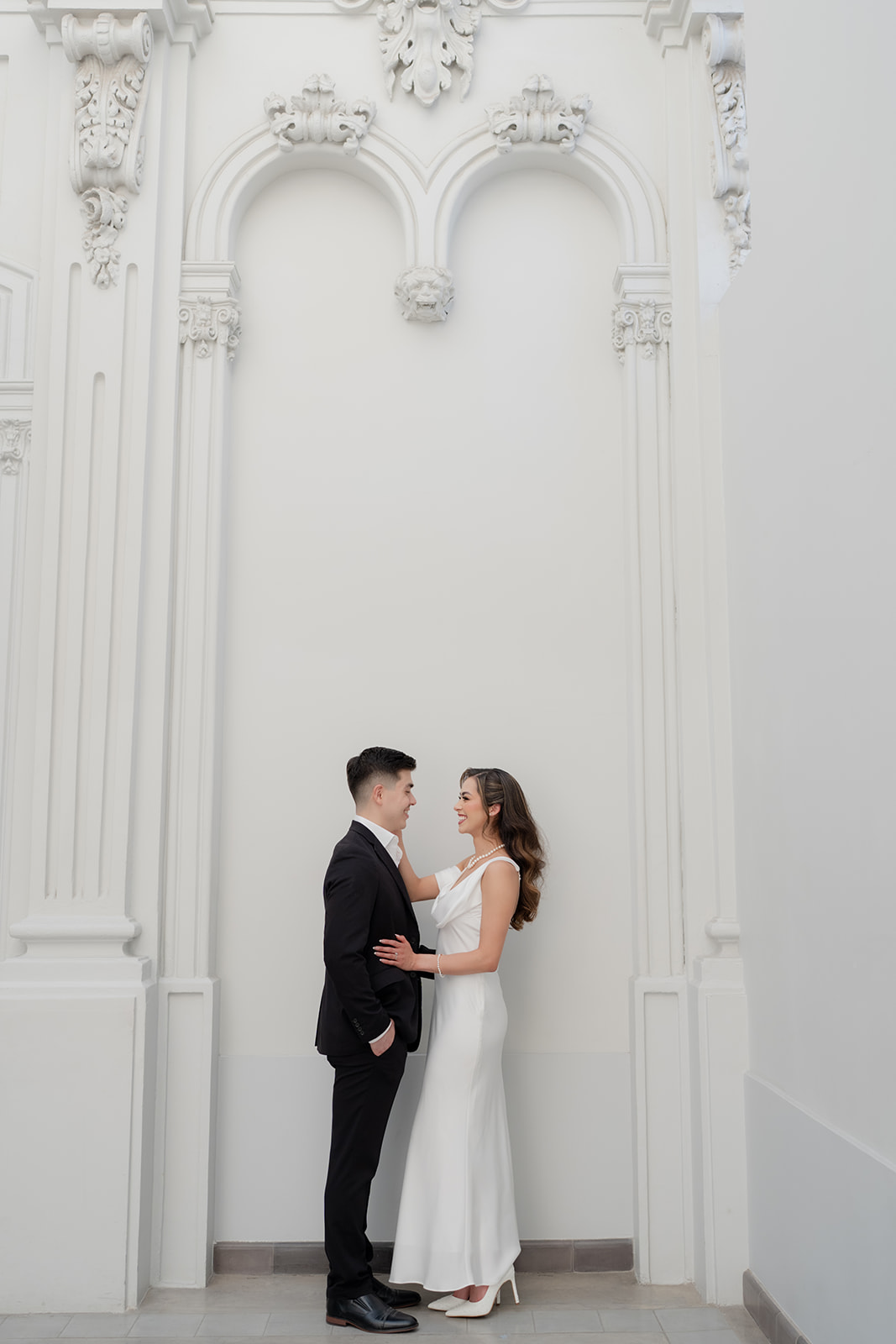 Full length portrait of Kelsey and Jose Elias beneath ornate white arches